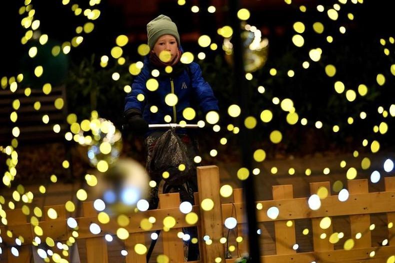Bé trai đạp xe để góp phần cung cấp năng lượng cho hệ thống đèn Giáng sinh ở một quảng trường tại Budapest, Hungary, nhằm tiết kiệm chi phí với việc sử dụng hệ thống đèn bền vững. (Ảnh: Reuters)